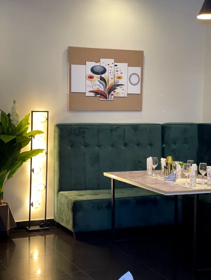 A green velvet booth with a marble table and globe lamp
